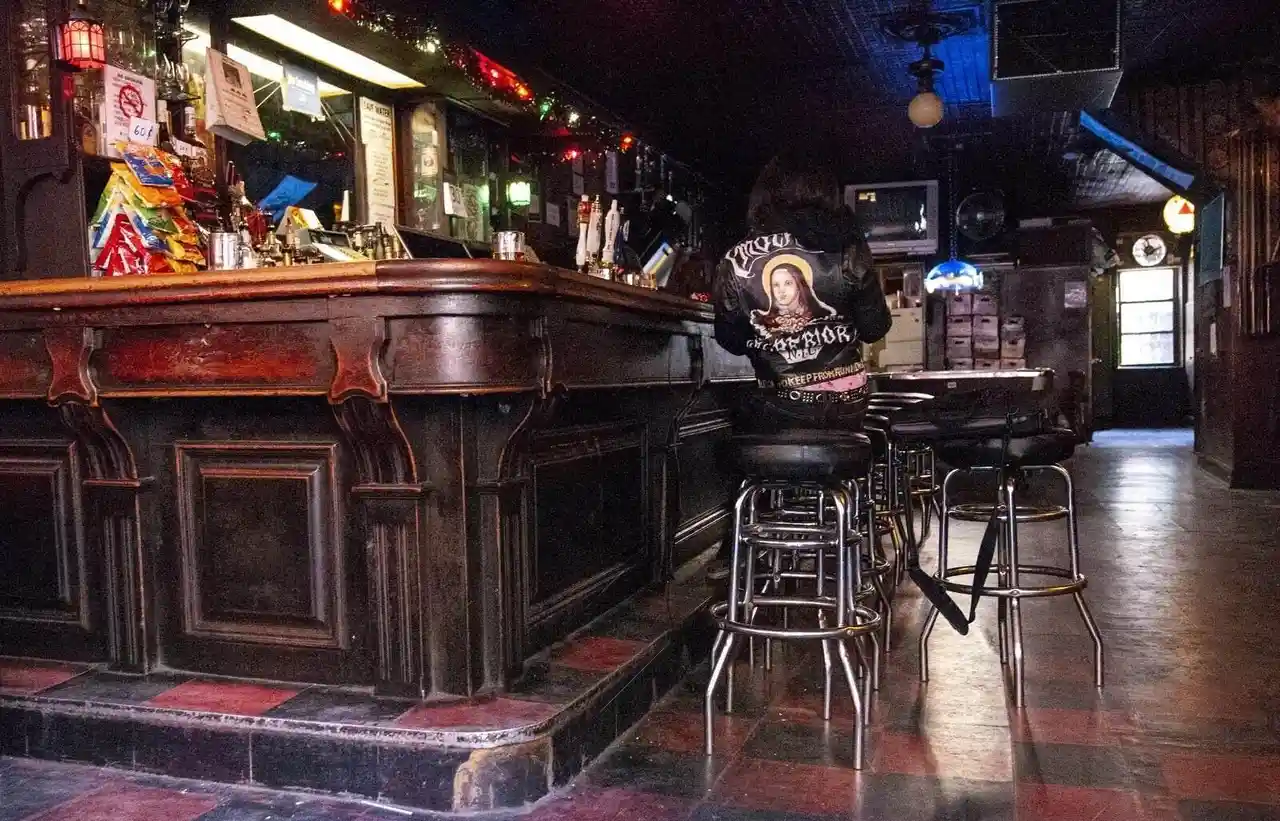 Person with graphic jacket at dive bar counter