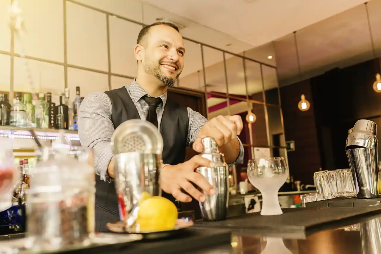 Smiling bartender preparing a drink with a shaker