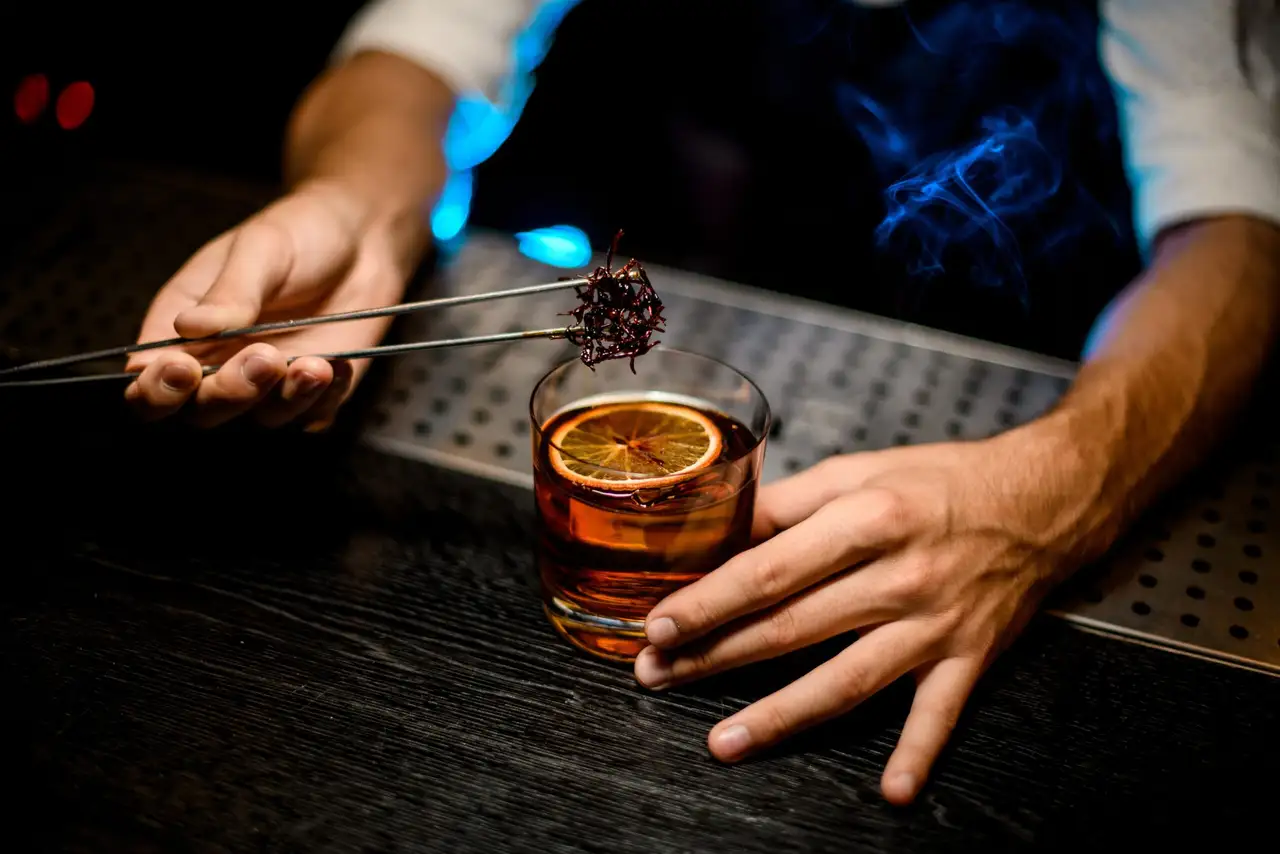 Bartender garnishing a smoked orange cocktail