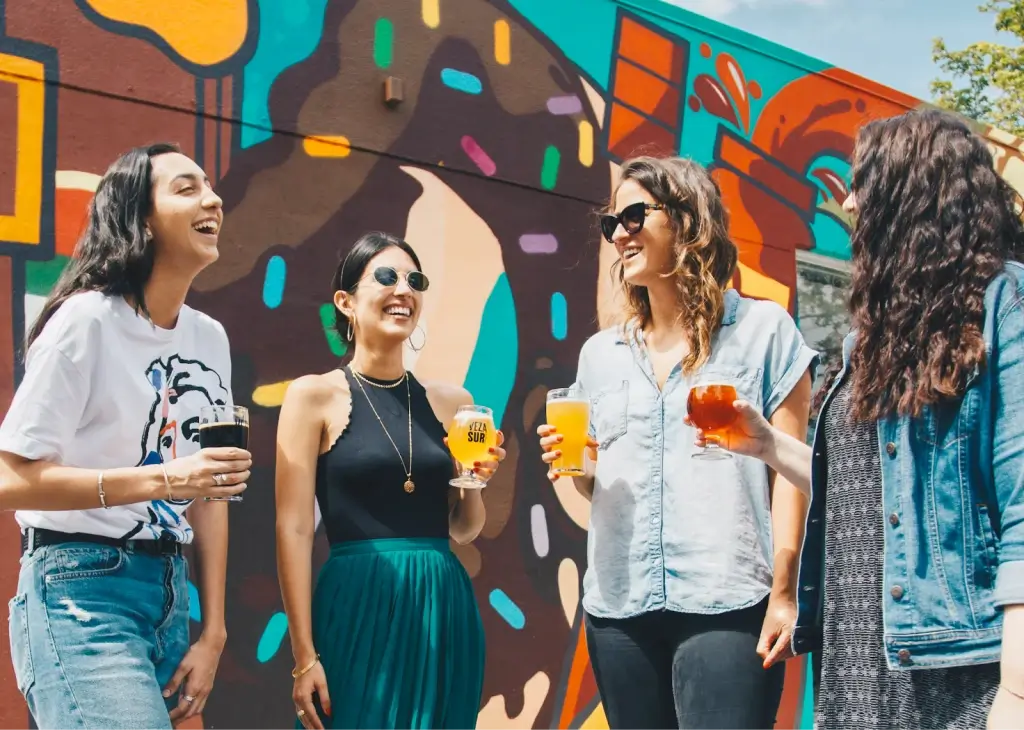 Four friends laughing and holding craft beers