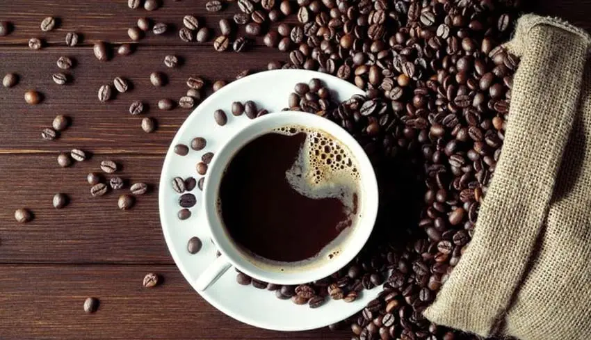 Overhead view of black coffee and roasted beans