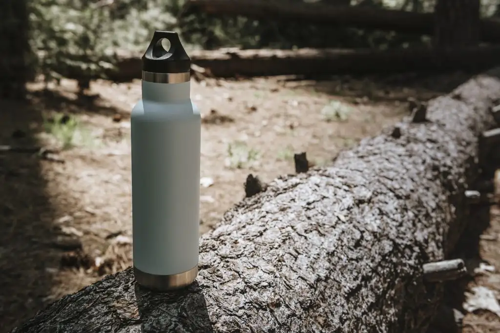 A reusable water bottle on a fallen log