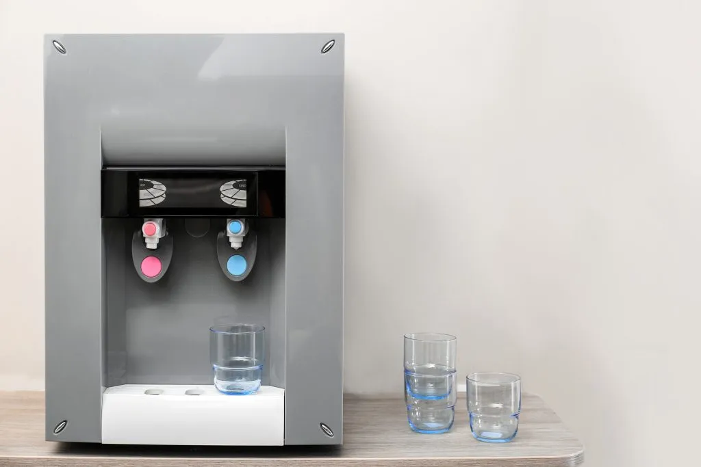 Modern water dispenser with glasses on a table