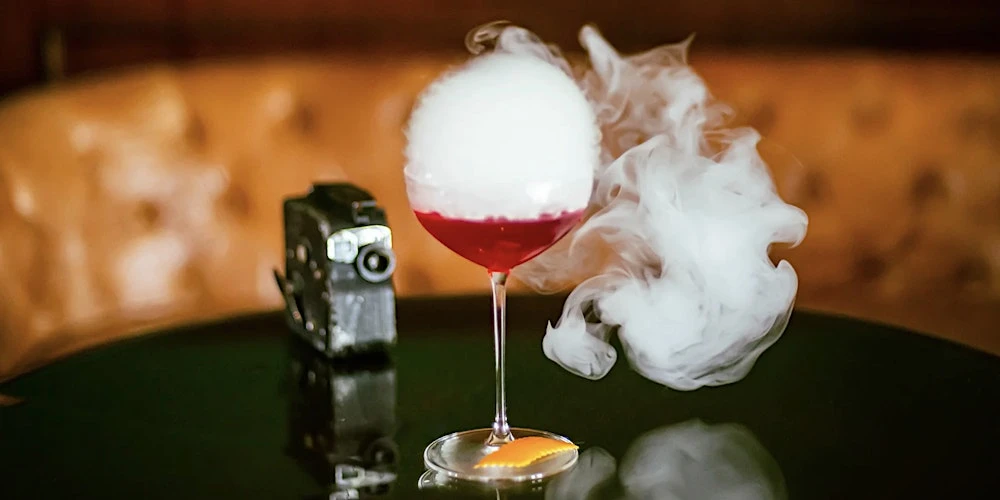Smoky, dramatic craft cocktail served in a coupe glass