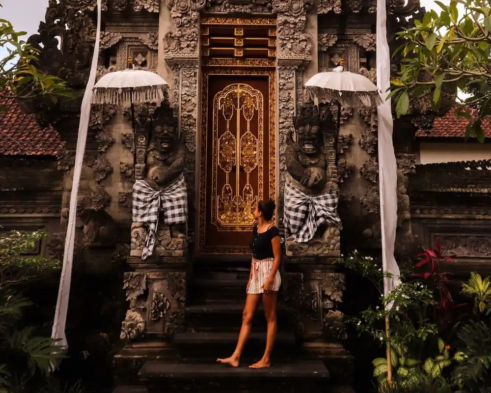 Woman standing before an ornate Balinese temple gate