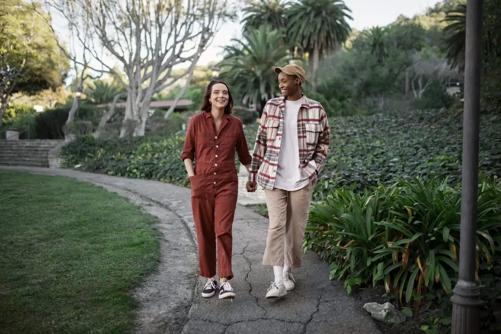 Two girls holding hands walking through a park