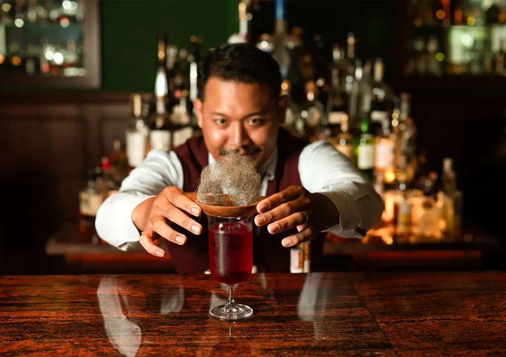craft cocktail bar with bartender presenting creative smoky drink in elegant lounge setting