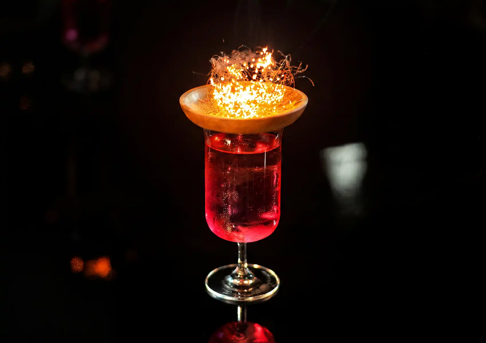 Signature cocktails Ubud with flaming citrus garnish in elegant glass