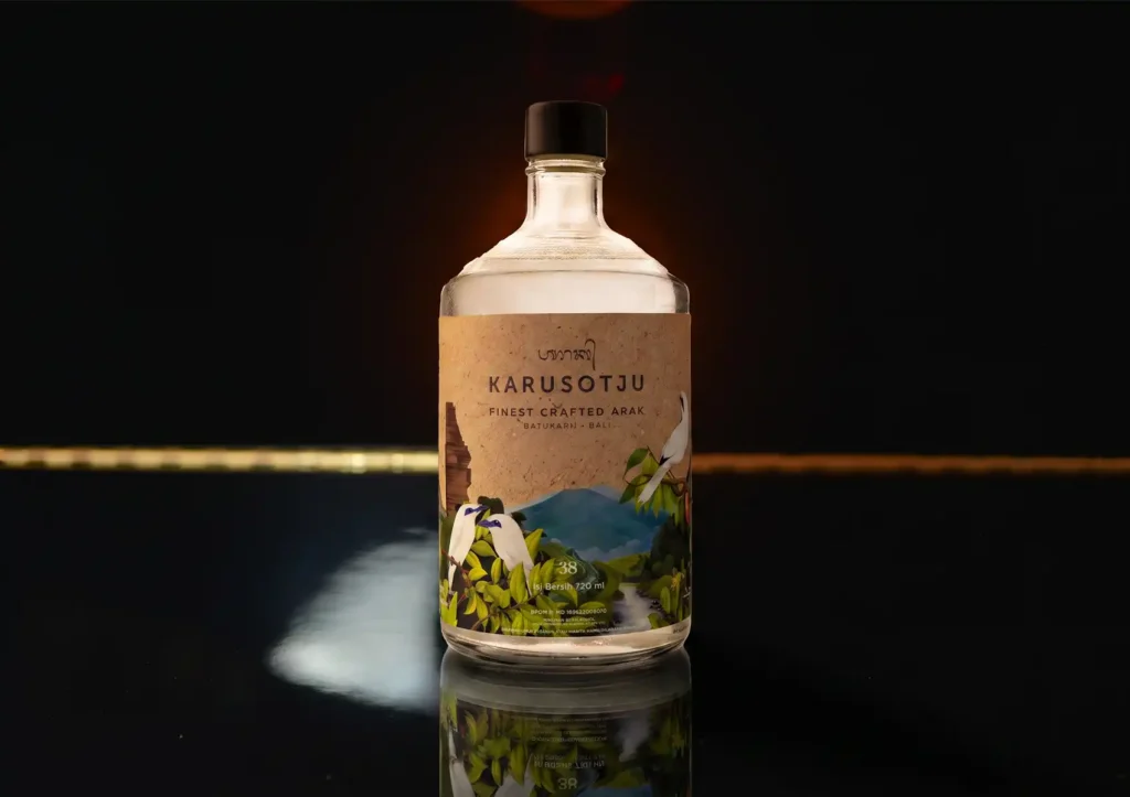 A bottle of Karusotju premium crafted Balinese arak displayed on a dark reflective counter at a cocktail bar ubud.